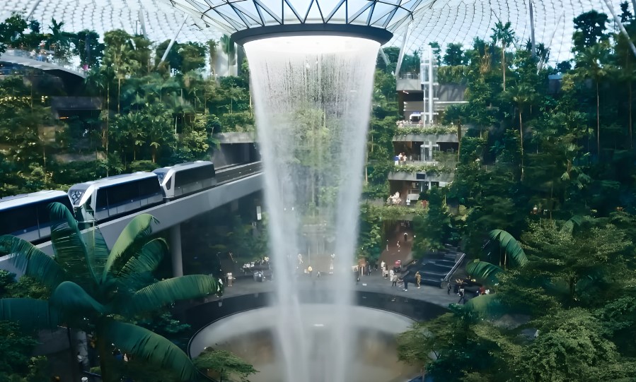 A captivating indoor waterfall, framed by a vibrant tropical garden at the Changi Airport